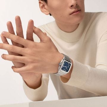 Photo of the Cartier Santos de Cartier 47.5 x 39.8mm Blue Dial Automatic Watch WSSA0071, showcasing a bold sunray-brushed blue dial with Roman numerals, sword-shaped hands, and a stainless steel case and bracelet